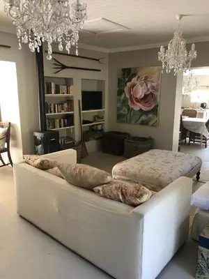 a living room with a white couch and a bed at Charming Rose Cottage in Greyton