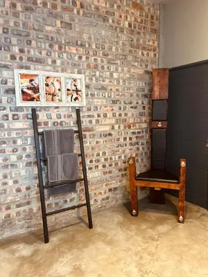 a room with a chair next to a brick wall at Tether and Tease, The Fortress in Cape Town