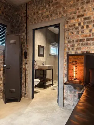 a bathroom with a brick wall and a mirror at Tether and Tease, The Fortress in Cape Town