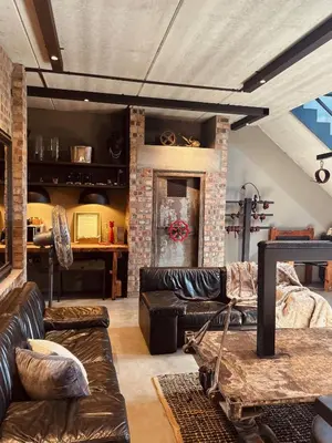 a living room with leather furniture and a brick fireplace at Tether and Tease, The Fortress in Cape Town