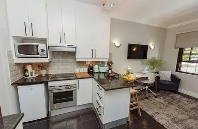 a kitchen with white cabinets and a table with a microwave at Studio in Central Stellenbosch in Stellenbosch