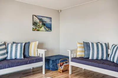two white benches sitting in a room with pillows at Villa Franlisa in Hermanus