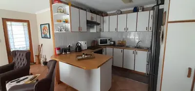 a kitchen with white cabinets and a wooden counter top at De Kleine Herberg in Durbanville