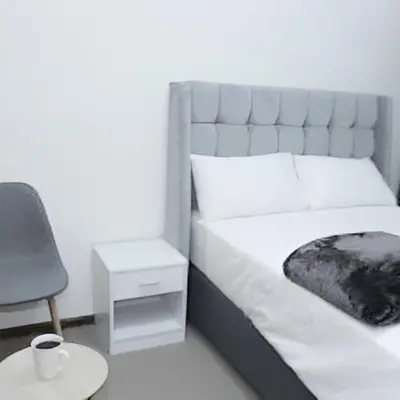 a bedroom with a bed with a chair and a table at Twinex Accommodation Parow in De Grendel