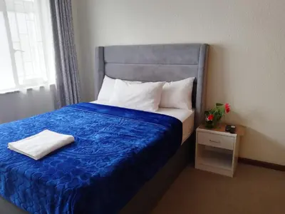 a bedroom with a bed with a blue comforter at Twinex Accommodation Parow in De Grendel