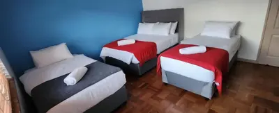 three beds in a room with a blue wall at Twinex Accommodation Bellville in Stikland