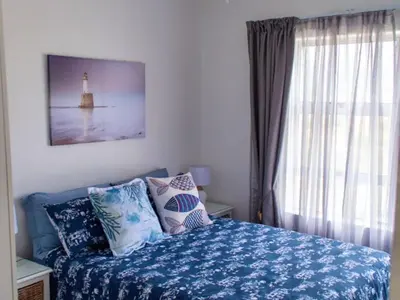 a bedroom with a bed with a lighthouse on it at Golfbeach Luxury self catering apartment in Cape Town