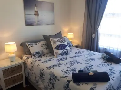 a bedroom with a blue and white bed with pillows at Golfbeach Luxury self catering apartment in Cape Town