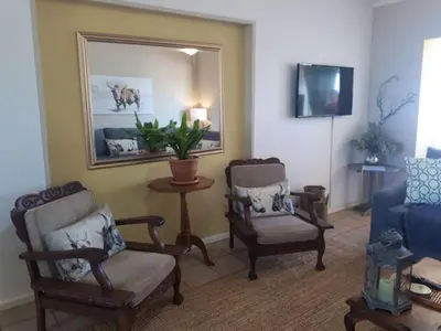 a living room with two chairs and a blue couch at Golfbeach Luxury self catering apartment in Cape Town