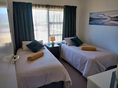 two beds in a room with a window at Golfbeach Luxury self catering apartment in Cape Town