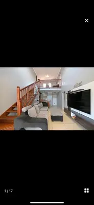 a living room with a couch and a television at YA Eagle Wings Self Catering Shared Single Room Lodge A in Cape Town