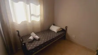 a small bed in a room with a window at Zoe Apartment in Cape Town