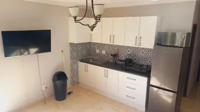 a kitchen with white cabinets and a stainless steel refrigerator at Zoe Apartment in Cape Town