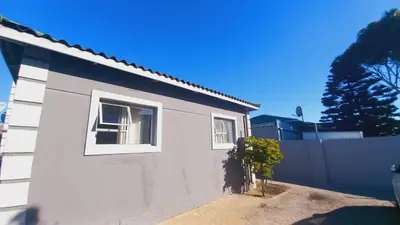 a white house with two windows and a fence at Zoe Apartment in Cape Town