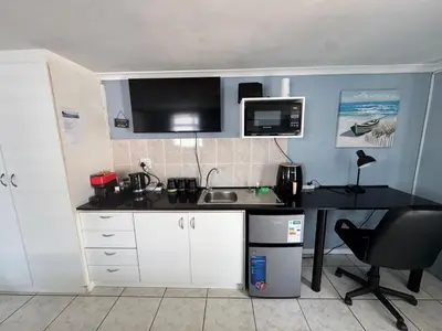 a kitchen with a desk with a sink and a microwave at Pemba Guest Cape Town in Cape Town