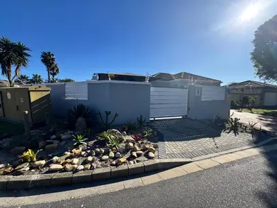 a backyard with a landscaping with rocks and a fence at Pemba Guest Cape Town in Cape Town