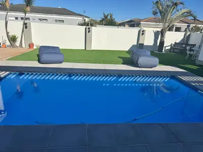 a swimming pool with blue water in a yard at Pemba Guest Cape Town in Cape Town