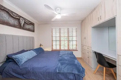 a bedroom with a blue bed and a desk at Serenity at Cape Bay in Helderberg