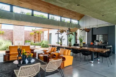 an open kitchen and living room with orange chairs and a bar at EersteBosch Cottages in Stellenbosch