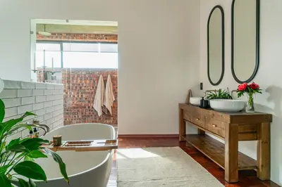 a bathroom with a tub and a sink and mirrors at EersteBosch Cottages in Stellenbosch