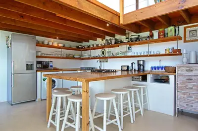 a kitchen with a wooden counter and bar stools at 82 Suikerbossie in Gordonʼs Bay