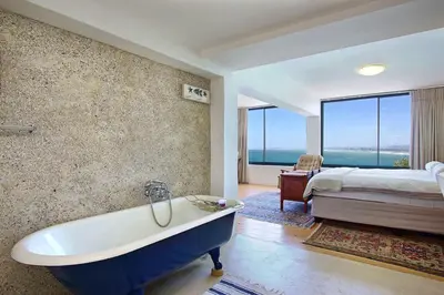 a bathroom with a tub and a bedroom with a bed at 82 Suikerbossie in Gordonʼs Bay