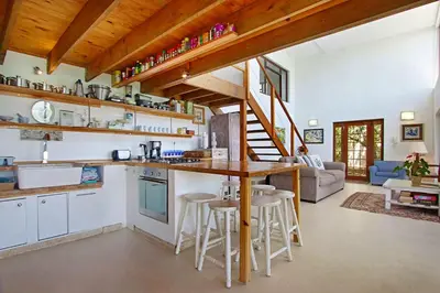 a kitchen and living room with a counter and stools at 82 Suikerbossie in Gordonʼs Bay