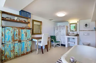a room with a desk and a table and a room with a kitchen at 82 Suikerbossie in Gordonʼs Bay
