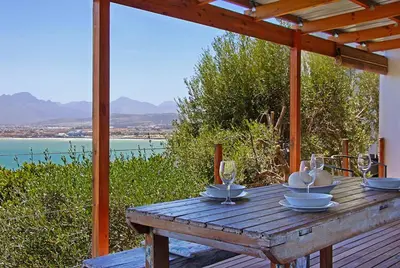 a wooden table with wine glasses on top of it at 82 Suikerbossie in Gordonʼs Bay