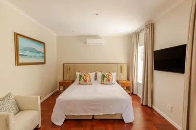a bedroom with a bed and a couch and a television at The Helderview Luxury Suites in Somerset West