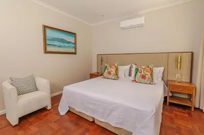 a bedroom with a white bed and a chair at The Helderview Luxury Suites in Somerset West