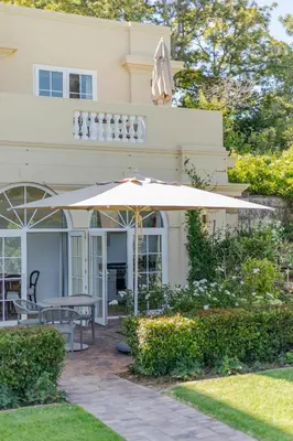 a patio with an umbrella in front of a house at The Helderview Luxury Suites in Somerset West