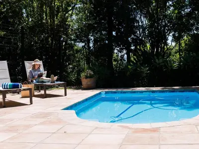 a woman sitting in a chair next to a swimming pool at Vendome Wine Estate in Paarl