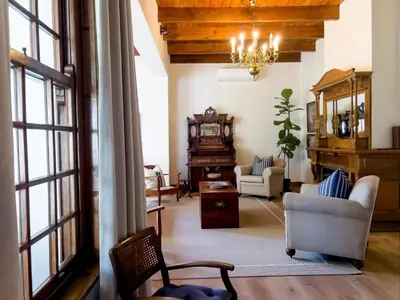 a living room with a couch and a chair and a piano at Vendome Wine Estate in Paarl