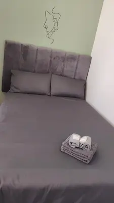 a bed with two towels and two pillows on it at Kenwyn Micro Apartments in Cape Town