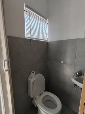 a small bathroom with a toilet and a sink at Kenwyn Micro Apartments in Cape Town