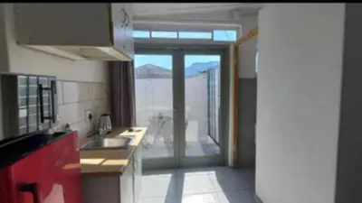 a kitchen with a door leading to a balcony at Kenwyn Micro Apartments in Cape Town
