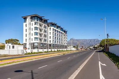 an empty street with a white building and mountains in the background at Lifestyle Accommodation in Cape Town