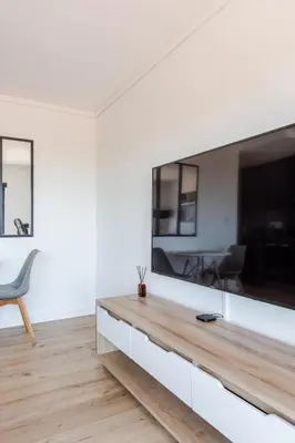 a living room with a large television on a white wall at Lifestyle Accommodation in Cape Town