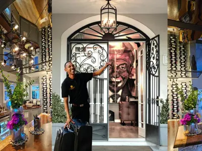 a man standing in front of a door with a suitcase at Fleur du Soleil Luxury Guesthouse in Franschhoek