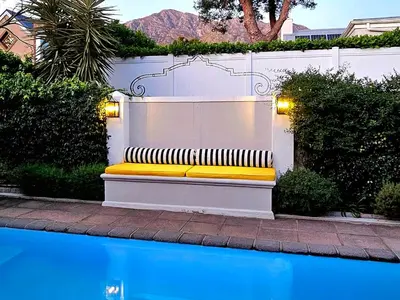 a yellow bench sitting next to a swimming pool at Fleur du Soleil Luxury Guesthouse in Franschhoek