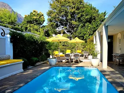 a swimming pool with an umbrella on a patio at Fleur du Soleil Luxury Guesthouse in Franschhoek