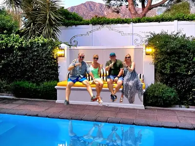 a group of people sitting on a bench next to a pool at Fleur du Soleil Luxury Guesthouse in Franschhoek