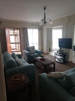 a living room with couches and a flat screen tv at Vues Du Mont in Hermanus