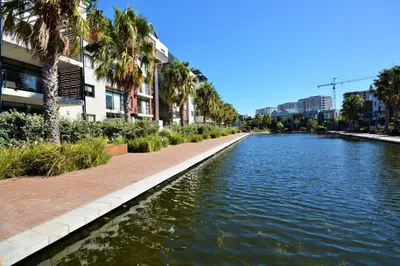 a canal of water with palm trees and buildings at Quayside 1 Bedroom Apartment in Century City in Cape Town