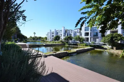 a river in a city with buildings in the background at Quayside 1 Bedroom Apartment in Century City in Cape Town