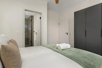 a white bed with two towels on top of it at On Park Apartments in Cape Town