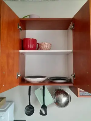 a kitchen cabinet with plates and utensils in it at Yannas Guesthouse in Cape Town