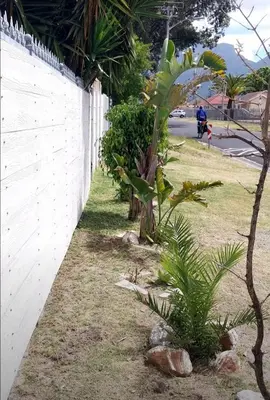 a white fence with plants next to a sidewalk at Yannas Guesthouse in Cape Town
