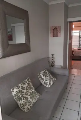 a living room with a gray couch with two pillows at Yannas Guesthouse in Cape Town